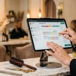 Salon professional using booking software on iPad at her station