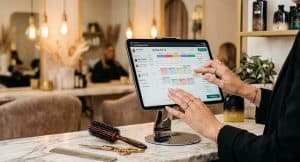 Salon professional using booking software on iPad at her station