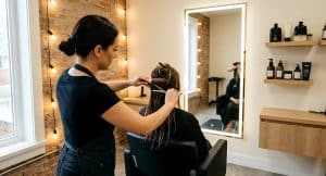 Hair stylist sectioning wet hair with shears in a private salon suite at Venus Salon Suites Frisco