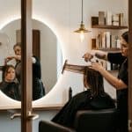 Hair stylist cutting client hair viewed through suite doorway