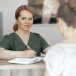Massage therapist meeting new client for the first time discussing service options.