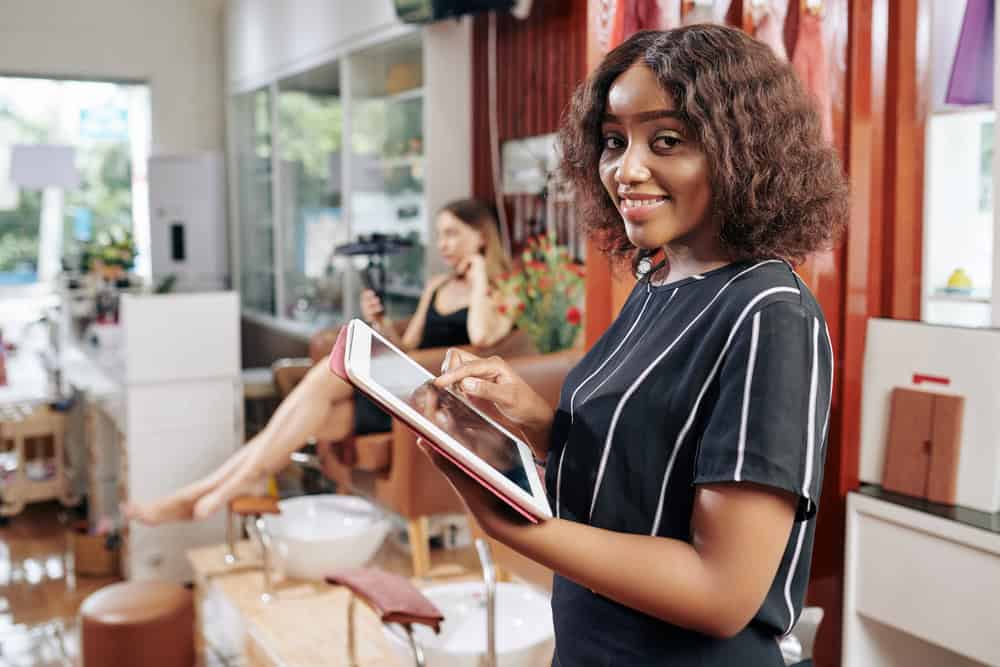 Woman using her table to work out her Hair Salon Business Tax and Insurance Needs